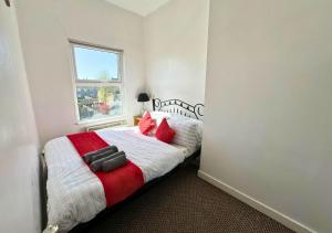 - une chambre avec un lit doté d'oreillers rouges et une fenêtre dans l'établissement Relaxing Getaway For Families With Free Parking, à Liverpool