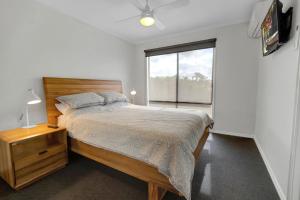 Un dormitorio con una cama y una ventana grande. en Mimada Escape, en Lakes Entrance