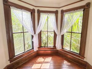 an empty room with large windows and wooden floors at Cozy Victorian Apartment Downtown Sleeps 5 in Gainesville +17 photos