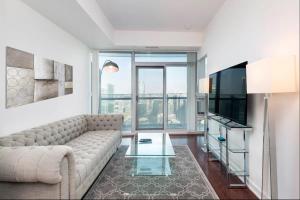 uma sala de estar com um sofá e uma televisão em Executive 1 BR Condo - CN Tower & City View em Toronto