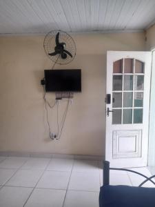 um quarto com uma televisão e uma ventoinha na parede em Apartamento em Muriqui/RJ - apt 203 em Mangaratiba