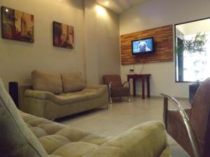 a living room with two chairs and a tv on the wall at Hotel Nolasco in Macaé