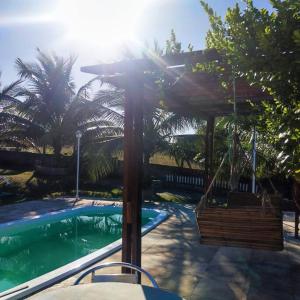 una piscina con pérgola de madera y un columpio en Paraíso do Brutus - casa de temporada en Beberibe