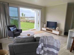 a living room with a couch and a television at Rata Karaka Bach in Ngunguru