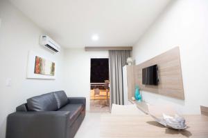 a living room with a black leather couch and a television at Atrium Thermas Flat Service - OFICIAL in Caldas Novas