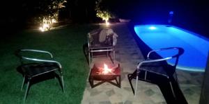 - deux chaises et un foyer extérieur à côté de la piscine la nuit dans l'établissement Recanto São Gabriel Socorro/SP chácara com linda Vista, à Socorro