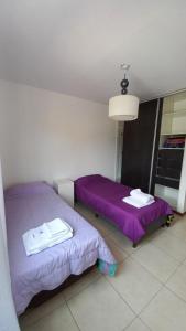 duas camas num quarto com lençóis roxos em Alojamiento en Luján de Cuyo em Ciudad Lujan de Cuyo