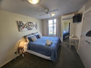 Schlafzimmer mit einem Bett mit blauer Decke in der Unterkunft Parkhill Accommodation in Whangarei