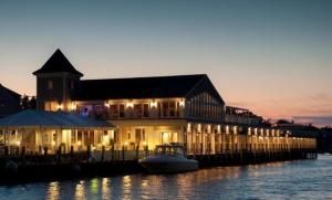 a dock with a building with a boat in the water at Wychmere Beach Club in Harwich Port