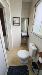 La salle de bains est pourvue de toilettes blanches et d'un lavabo. dans l'établissement Bella Praia Apartamento Remo, à Passo de Torres