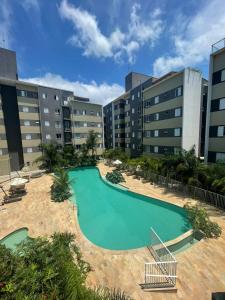 a large swimming pool in the middle of a building at Jardim das Palmeiras II Home Resort JP2 Ubatuba - Apartamento com 2 Dorms, 1 Suíte, Churrasqueira Gourmet, Piscina Adulto e Infantil, Jacuzzi Aquecida, Sauna, Academia, Salão de Jogos e Playground in Ubatuba