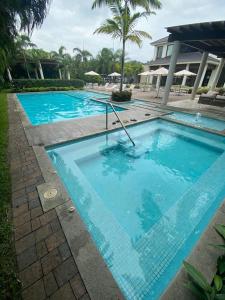 a large blue swimming pool next to a building at Minisuite entrada lateral, seguridad y privacidad in SamborondÃ³n