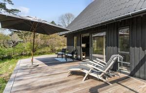 una terrazza in legno con due sedie e un ombrellone di 2 Bedroom Cozy Home In Tisvildeleje a Tisvildeleje