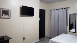 um quarto com uma cama e uma televisão de ecrã plano na parede em Casa Altamira em San Pedro Sula