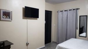 a bedroom with a bed and a flat screen tv on a wall at Casa Altamira in San Pedro Sula