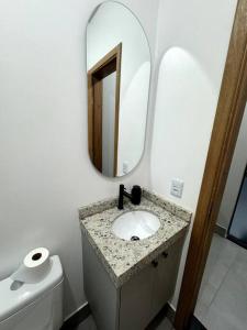 een badkamer met een wastafel en een spiegel en een toilet bij 2- Studio Prox Uel e catuai c/ar in Londrina +10 foto's
