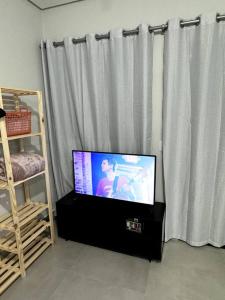 een flatscreen-tv voor een gordijn bij 2- Studio Prox Uel e catuai c/ar in Londrina