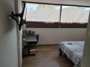 a room with a bed and a desk and a window at Departamento Privado7, 2 camas matri, parking, cocina equipada, wifi 65 mb, 2 Climas,Centrico,Tv smart in Ciudad Valles