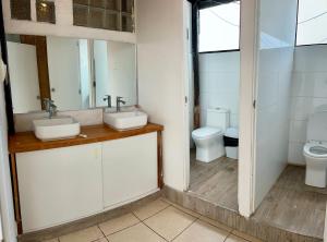 a bathroom with two sinks and a toilet at Bravo Surf Camp in Punta Hermosa