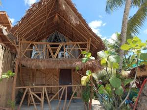 a thatch roofed hut on a beach with palm trees at 8 Star Paradise in Locaroc