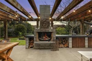 an outdoor patio with a fireplace with a table and a bench at The Mangawhai Bach in Mangawhai