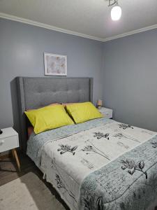 um quarto com uma cama com almofadas amarelas em Departamento Puertas del Mar em La Serena