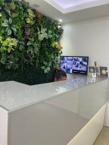 Una persona sentada en un mostrador con una pared vegetal. en Hotel Areião, en Goiânia