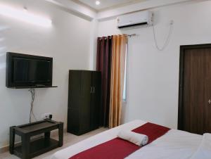 1 dormitorio con 1 cama, TV y mesa en The Champ Palace en Lucknow