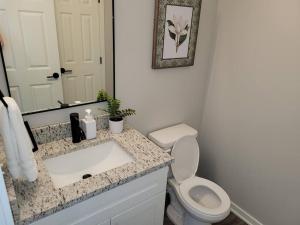 a bathroom with a sink and a toilet and a mirror at The Prairie at Coventry Rows in Omaha