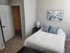 a white bed with blue pillows in a bedroom at The Prairie at Coventry Rows in Omaha