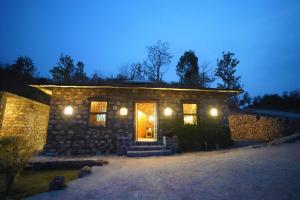 una casa de piedra con una puerta iluminada por la noche en Dirghayu Bhava Retreat, en Dehradun