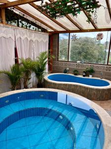 een groot zwembad met twee jacuzzi's in een huis bij Sinestesia House in Baños