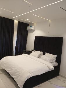 duże białe łóżko z czarnym zagłówkiem w pokoju w obiekcie 3 Bedroom Luxury Duplex (terrace) w Enugu