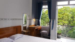 1 dormitorio con cama, escritorio y ventana en Sunny Homestay Quy Nhơn en Quy Nhon