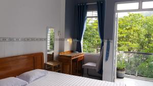 a bedroom with a bed and a desk and a window at Sunny Homestay Quy Nhơn in Quy Nhon