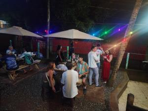 un grupo de personas de pie alrededor de una mesa por la noche en Fenix Hotel & Hostel, en Utila