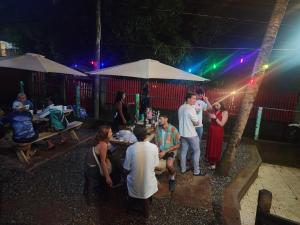 a group of people standing around a table at night at Fenix Hotel & Hostel in Utila