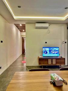 ein Wohnzimmer mit einem TV und einem Tisch in der Unterkunft Brand New Two-Bedroom Villa with rice field views. in Tanah Lot