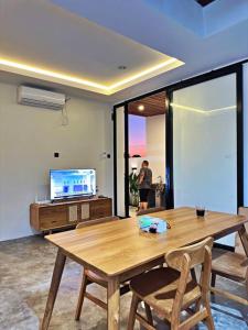 einen Holztisch und Stühle in einem Zimmer mit einem TV in der Unterkunft Brand New Two-Bedroom Villa with rice field views. in Tanah Lot