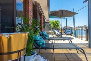 drie stoelen en een parasol op een patio bij Southern River Canal Retreat in South Yunderup