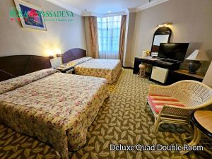 a hotel room with two beds and a mirror at Hotel Rosa Passadena in Cameron Highlands