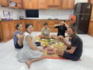 eine Gruppe von Menschen, die in einer Küche auf dem Boden sitzen in der Unterkunft Homestay Sea View Ông Hoành 