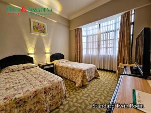 a hotel room with two beds and a television at Hotel Rosa Passadena in Cameron Highlands