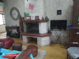 sala de estar con chimenea y TV en Guest House sítio do Sol Penedo, en Penedo