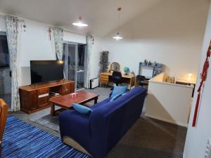 a living room with a blue couch and a tv at An inner city 4-bedroom house with two carparks in Wellington