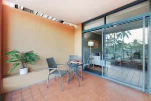 um quarto com uma mesa e cadeiras e uma varanda em 'Harbour Highlight' Poolside Living on Esplanade em Darwin
