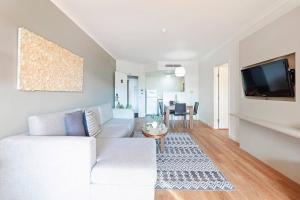 uma sala de estar com um sofá branco e uma televisão em 'Harbour Highlight' Poolside Living on Esplanade em Darwin
