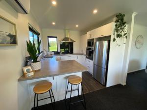 a kitchen with a large island with two bar stools at Soul Sanctuary, with outdoor bath in Raglan