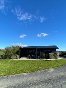 a large black building with a blue sky at Soul Sanctuary, with outdoor bath in Raglan