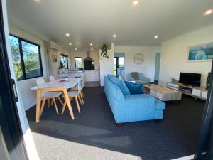 a living room with a blue couch and a table at Soul Sanctuary, with outdoor bath in Raglan